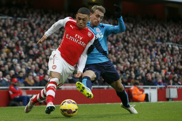 Arsenal's Alex Oxlade-Chamberlain, left, controls the ball past Stoke City’s Marc Muniesa during their English Premier League soccer match between Arsenal and Stoke City at the Emirates stadium in London, Sunday, Jan. 11, 2015. (AP Photo/Alastair Grant)