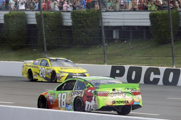 Matt Kenseth (20) drives back up the front stretch past a coasting Kyle Busch (18) after winning the NASCAR Pocono 400 auto race, Sunday, Aug. 2, 2015, in Long Pond, Pa. Busch was leading the race when he ran out of fuel on the final lap. (AP Photo/Matt Slocum)