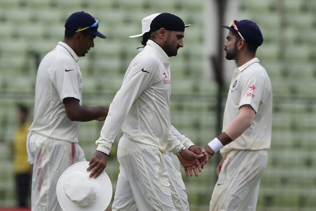 Indian cricket captain  Virat Kohli (L), Ravichandran Ashwin (R) and Harbhajan Singh (C) walk off the field during the final day of the cricket Test match between Bangladesh and India at Khan Shaheb Osman Ali Stadium in Narayanganj on June 14, 2015. AFP PHOTO/Munir uz ZAMAN        (Photo credit should read MUNIR UZ ZAMAN/AFP/Getty Images)