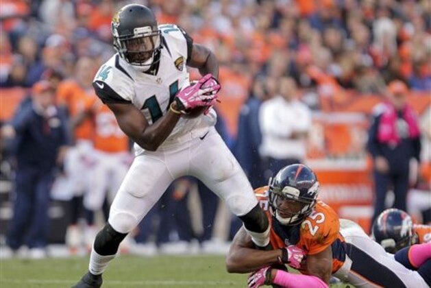 FILE - In this Oct. 13, 2013, file photo, Jacksonville Jaguars wide receiver Justin Blackmon (14) tries to pull away from Denver Broncos cornerback Chris Harris (25) after catching pass during an NFL football game in Denver. Suspended Jaguars receiver Blackmon has checked into a voluntary treatment program and seems to be doing well. Coach Gus Bradley told The Associated Press on Wednesday, Oct. 1, 2014, that the former Oklahoma State star and 2012 first-round NFL draft pick “is doing very well and he’s learning a lot.” Bradley says he is getting updates from Blackmon’s agent. (AP Photo/Joe Mahoney, FIle)