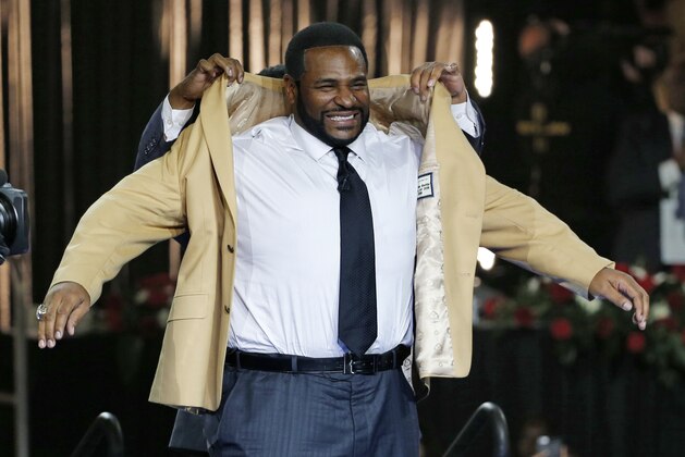 Pro Football Hall of Fame inductee Jerome Bettis slips into his gold jacket with help from presenter, brother John Bettis III, rear, during the Gold Jacket Ceremony in Canton, Ohio, Thurdsday, August 6, 2015. (AP Photo/Gene J. Puskar)
