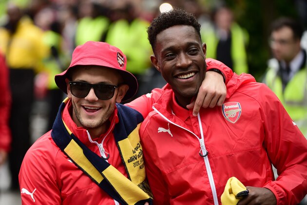 Arsenal's English midfielder Jack Wilshere and Arsenal's English striker Danny Welbeck react during the Arsenal victory parade in London on May 31, 2015, following their win in the English FA Cup final football match on May 30, 2014 against Aston Villa. Arsene Wenger's side made history at Wembley with a 4-0 rout of Aston Villa that underlined their renaissance in the second half of the campaign and served as a warning to English champions Chelsea.     AFP PHOTO / LEON NEAL        (Photo credit should read LEON NEAL/AFP/Getty Images)