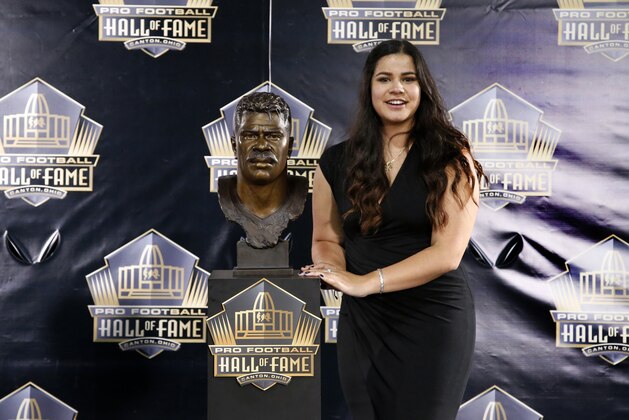 Daughter of former NFL player Junior Seau, Sydney Seau poses with a bust of her father during an induction ceremony at the Pro Football Hall of Fame Saturday, Aug. 8, 2015, in Canton, Ohio. (AP Photo/Gene J. Puskar)