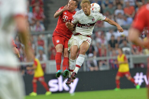 Munich's Rafinha, left challenge for the ball with Milan's Keisuke Honda during the friendly soccer match between FC Bayern and AC Milan, in the Allianz Arena stadium in Munich, southern Germany, Tuesday, Aug. 4, 2015. (AP Photo/Kerstin Joensson)