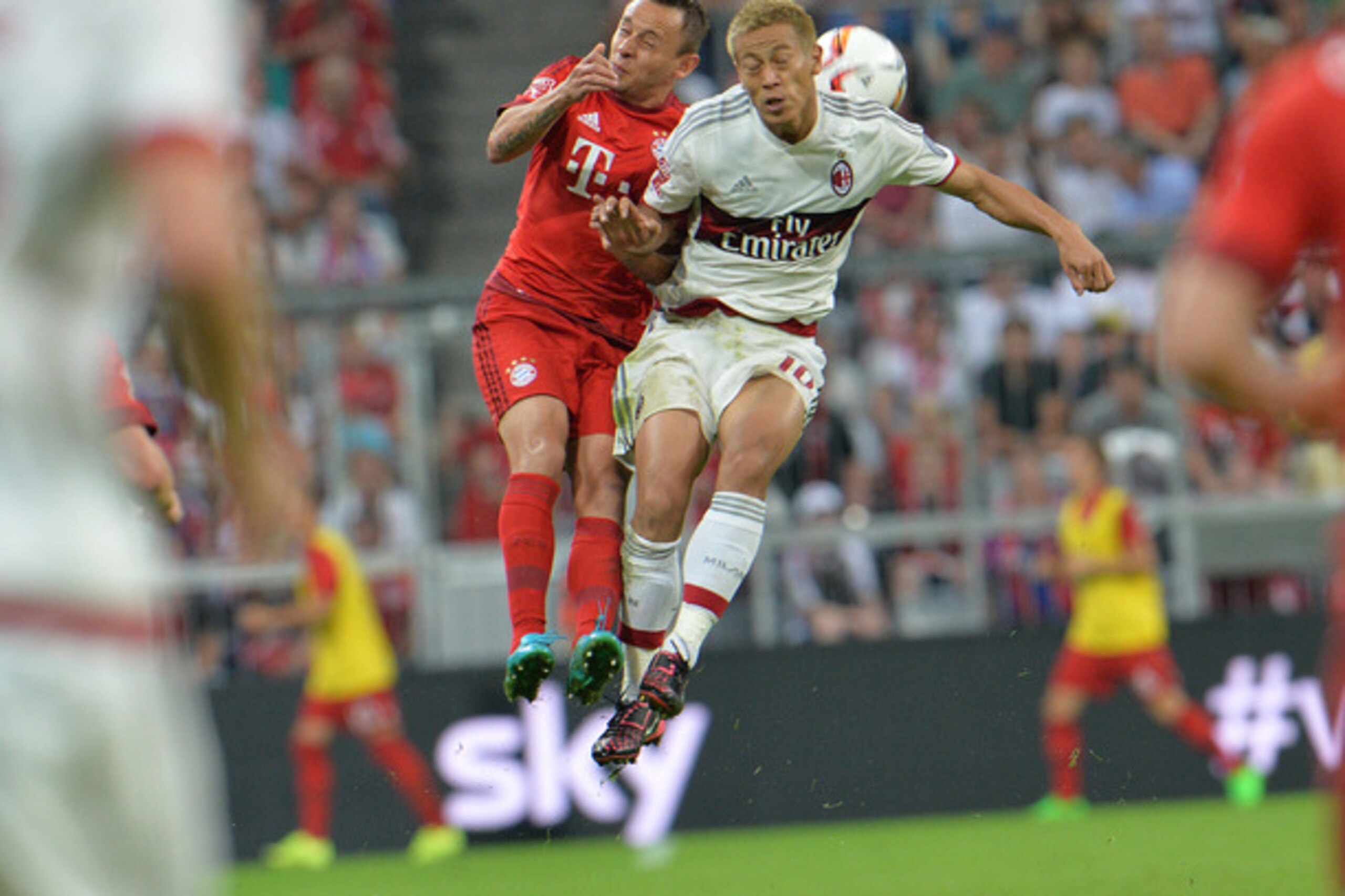 Munich's Rafinha, left challenge for the ball with Milan's Keisuke Honda during the friendly soccer match between FC Bayern and AC Milan, in the Allianz Arena stadium in Munich, southern Germany, Tuesday, Aug. 4, 2015. (AP Photo/Kerstin Joensson)