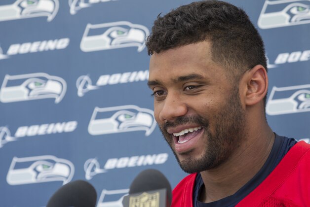 Seattle Seahawks quarterback Russell Wilson smiles during a press conference after an NFL football training camp on Friday, July 31, 2015, in Renton, Wash. Wilson signed a four-year $87 million contract. (AP Photo/Stephen Brashear)