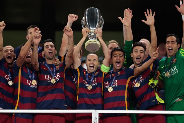 Barcelona's team captain Andres Iniesta lifts the trophy after winning the UEFA Super Cup soccer match between FC Barcelona and Sevilla FC at the Boris Paichadze Dinamo Arena stadium, in Tbilisi, Georgia, on Wednesday, Aug. 12, 2015. Barcelona won 5-4. (AP Photo/Ivan Sekretarev)