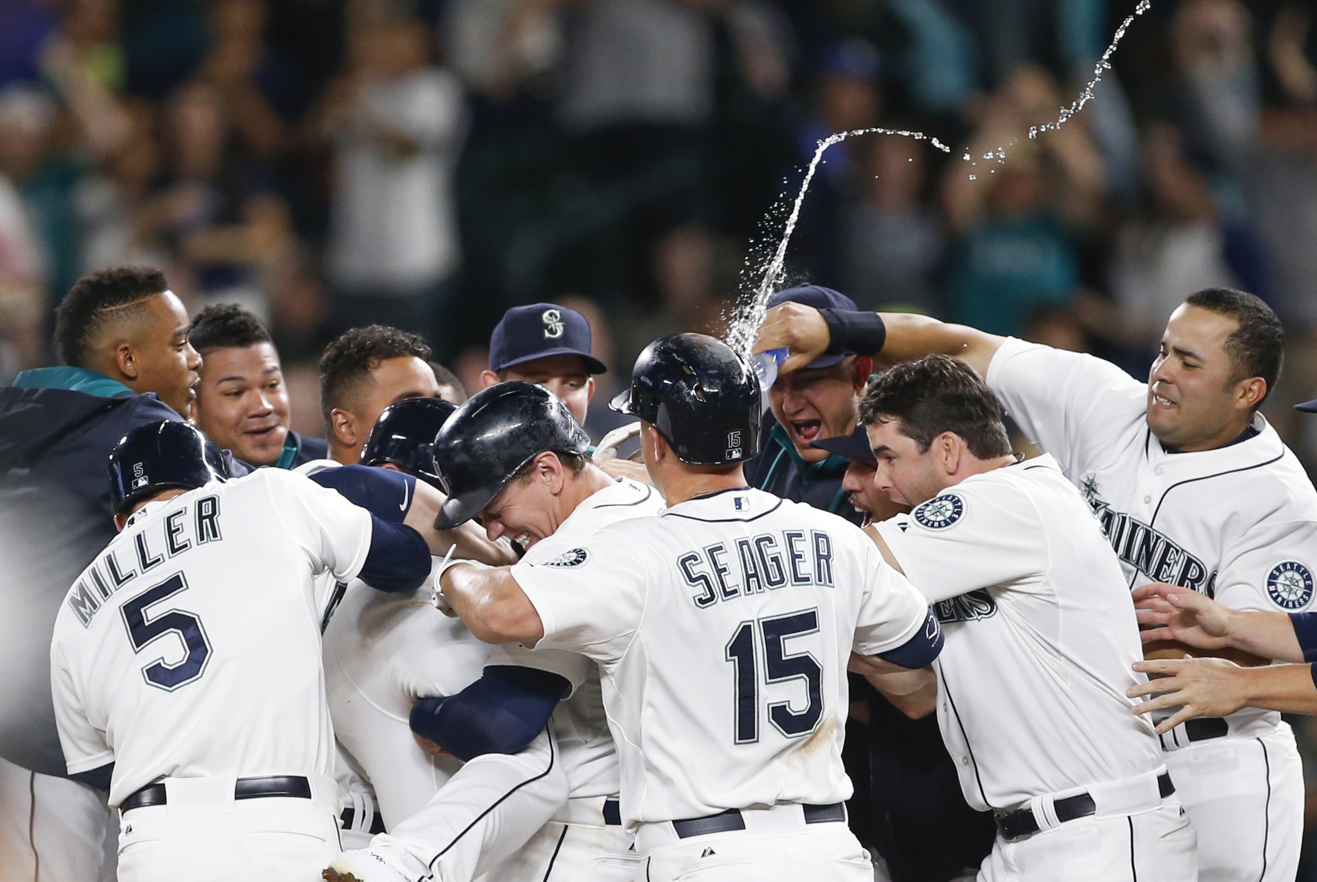 Aug 11, 2015; Seattle, WA, USA; Seattle Mariners right fielder Logan Morrison (20, middle left) is doused by first baseman Jesus Montero (63, right) as he picks up center fielder Austin Jackson (16, legs) after a game-winning RBI-single by Jackson against the Baltimore Orioles during the tenth inning at Safeco Field. Seattle defeated Baltimore, 6-5. Mandatory Credit: Joe Nicholson-USA TODAY Sports