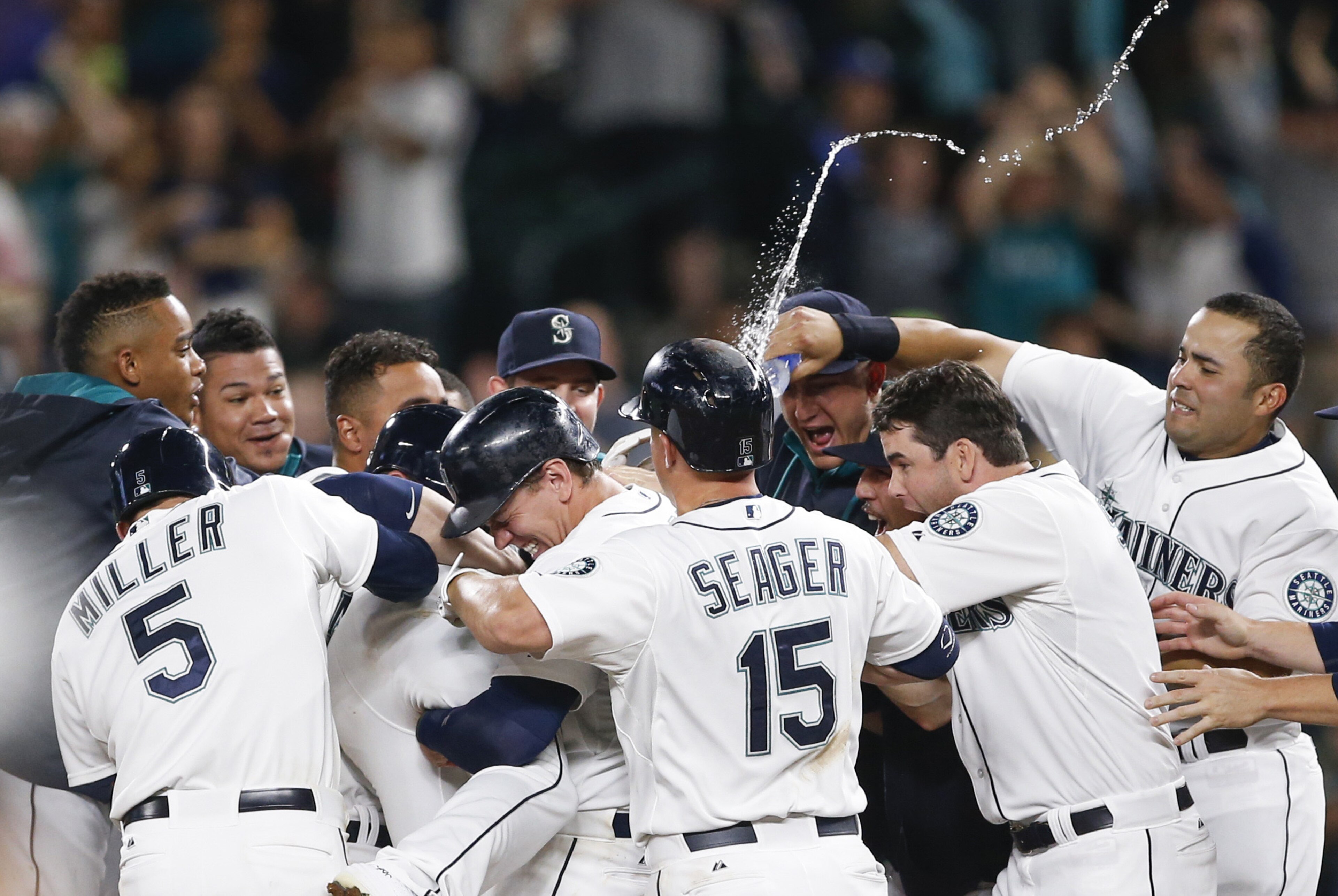 Aug 11, 2015; Seattle, WA, USA; Seattle Mariners right fielder Logan Morrison (20, middle left) is doused by first baseman Jesus Montero (63, right) as he picks up center fielder Austin Jackson (16, legs) after a game-winning RBI-single by Jackson against the Baltimore Orioles during the tenth inning at Safeco Field. Seattle defeated Baltimore, 6-5. Mandatory Credit: Joe Nicholson-USA TODAY Sports