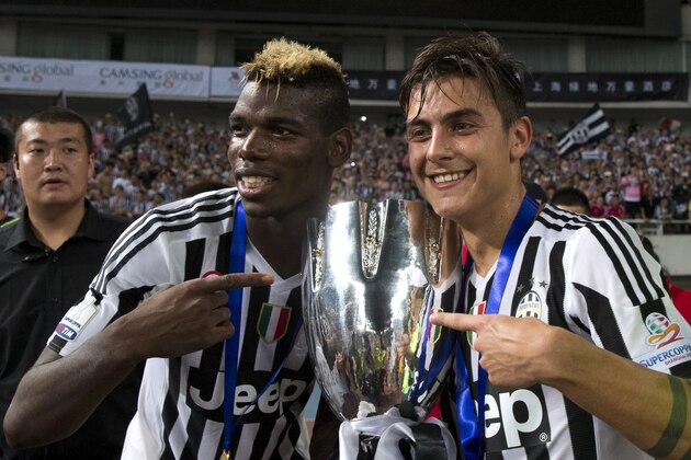 Juventus' Paulo Dybala, right and Paul Labile Pogba pose with the trophy after beating Lazio during the 2015 TIM Italian Supercup held at the Shanghai Stadium in Shanghai, China, Saturday, Aug. 8, 2015. Juventus defeat Lazio 2-0 to win the Supercup. (AP Photo/Ng Han Guan)