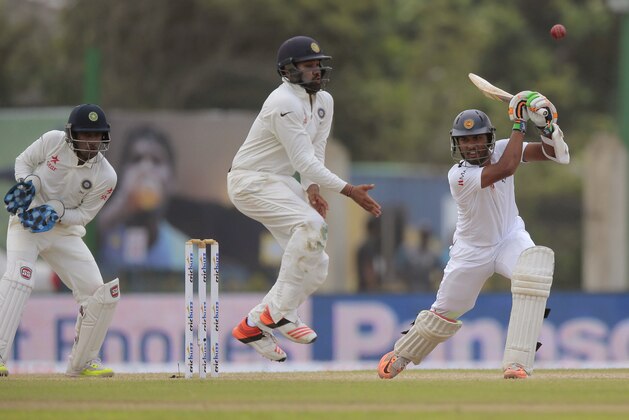 India's Rohit Sharma, center, jumps to avoid the ball being hit off a shot of Sri Lanka's Dinesh Chandimal, right, as wicketkeeper Wriddhiman Saha watches during the third day of the first cricket test match between India and Sri Lanka in Galle, Sri Lanka, Friday, Aug. 14, 2015. (AP Photo/Eranga Jayawardena)