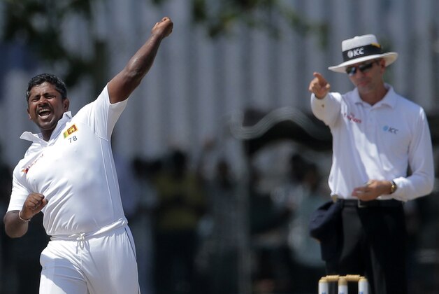 Sri Lanka's Rangana Herath, left, celebrates the dismissal of India's Ishant Sharma as the umpire signals his decision during the fourth day of their first test cricket match in Galle, Sri Lanka, Saturday, Aug. 15, 2015. (AP Photo/Eranga Jayawardena)
