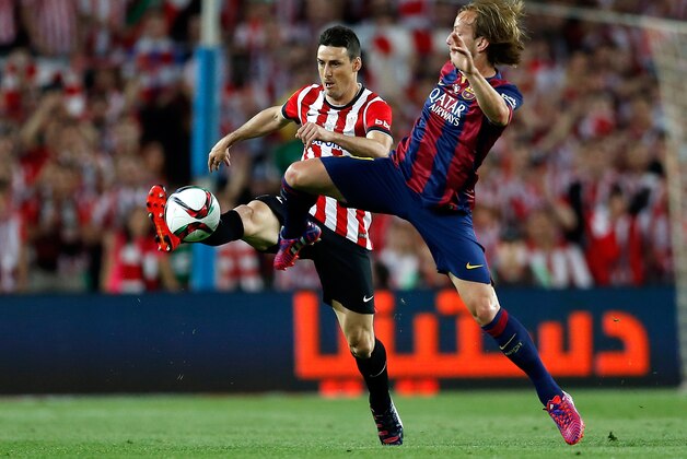 Athletic Bilbao's Aritz Aduriz, left, fights for the ball with Barcelona's Ivan Rakitic during the final of the Copa del Rey soccer match between FC Barcelona and Athletic Bilbao at the Camp Nou stadium in Barcelona, Spain, Saturday, May 30, 2015. (AP Photo/Manu Fernandez)