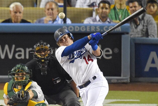 Los Angeles Dodgers' Kike Hernandez, right, hits an RBI double as Oakland Athletics catcher Stephen Vogt, left, and home plate umpire Brian Knight watch during the seventh inning of a baseball game, Wednesday, July 29, 2015, in Los Angeles. (AP Photo/Mark J. Terrill)