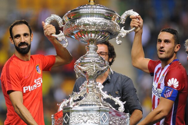 Atletico Madrid's defender Juanfran (L) and Atletico Madrid's midfielder Koke (R) pose with the trophy after winning the Trofeo Carranza football match Atletico de Madrid vs Betis at the Ramon de Carranaza stadium in Cadiz on August 15, 2015. Atletico de Madrid won 3-0.  AFP PHOTO / CRISTINA QUICLER        (Photo credit should read CRISTINA QUICLER/AFP/Getty Images)