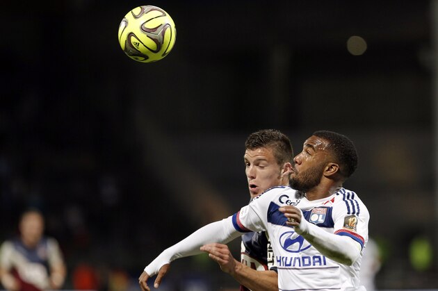 Lyon's Alexandre Lacazette, right, challenges for the ball with Bordeaux' Frederic Guilbert,  during the French League One soccer match between Lyon and Bordeaux, in Lyon, central France, Saturday, May 16, 2015. (AP Photo/Laurent Cipriani)