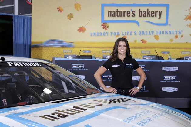Danica Patrick poses by her new race car during a news conference to announce a new sponsorship for her NASCAR auto racing team at Stewart-Haas Racing's headquarters in Kannapolis, N.C., Tuesday, Aug. 18, 2015. (AP Photo/Chuck Burton)