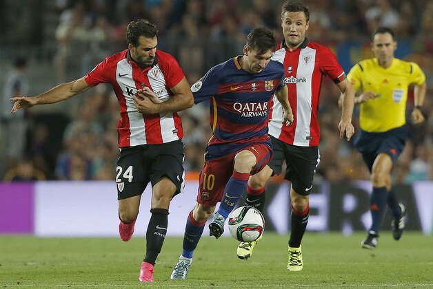 Barcelona's Lionel Messi, center, and Athletic Bilbao's Mikel Balenziaga challenge for the ball during the second leg Spanish Super Cup soccer match between FC Barcelona and Athletic Bilbao at the Camp Nou stadium in Barcelona, Spain, Monday, Aug.17, 2015. (AP Photo/Emilio Morenatti)