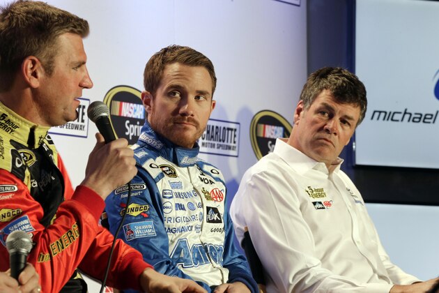 Driver Clint Bowyer, left, speaks to the media as team owner Michael Waltrip, right, and driver Brian Vickers, center, listen during the NASCAR Charlotte Motor Speedway media tour in Charlotte, N.C., Tuesday, Jan. 27, 2015. (AP Photo/Chuck Burton)