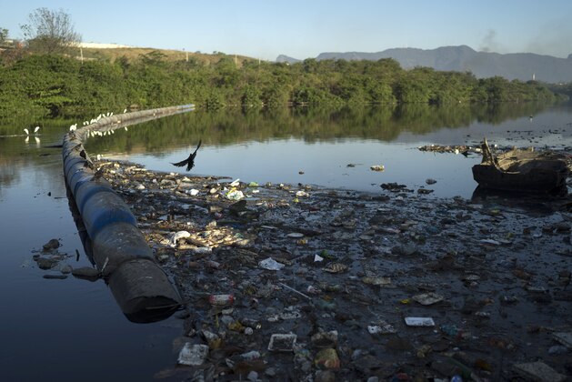 Trash abuts floating waste barriers in a canal at the Mare slum complex, in Rio de Janeiro, Brazil, Friday, July 31, 2015. Rio's historic sewage problem spiraled over the past decade as the population exploded with many of the metropolitan area's 12 million residents settling in the vast slums that ring the bay. Waste flows into over 50 streams that empty into the once-crystalline Guanabara Bay. (AP Photo/Leo Correa)