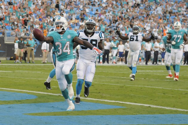 Miami Dolphins' Damien Williams (34) runs past Carolina Panthers' Thomas Davis (58) for a touchdown during the first half of an NFL preseason football game in Charlotte, N.C., Saturday, Aug. 22, 2015. (AP Photo/Mike McCarn)