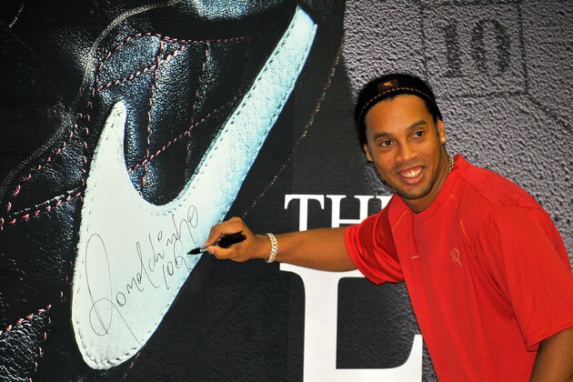 Brazilian football star Ronaldinho signs his autograph on a advertisement board after a football lesson with South Korean middle school students in Seoul on July 2, 2008. Ronaldinho is touring Asia as part of a trip aimed at promoting Nike football shoes. AFP PHOTO/JUNG YEON-JE (Photo credit should read JUNG YEON-JE/AFP/Getty Images)