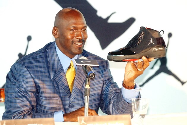 NBA legend Michael Jordan holds up an autographed AJ19 shoe, the latest design in the Air Jordan shoe line, at a Hong Kong news conference Friday, May 21, 2004. The American basketball great is on an Asian tour to promote his Jordan brand. He said Chinese NBA players such as Yao Ming will help draw more talent from China. (AP Photo/Anat Givon)