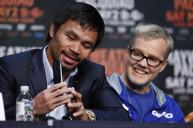 Manny Pacquiao, left, shows his phone to trainer Freddie Roach during a news conference Wednesday, April 29, 2015, in Las Vegas. Pacquiao will face Floyd Mayweather Jr. in a welterweight boxing match in Las Vegas on May 2. (AP Photo/John Locher)