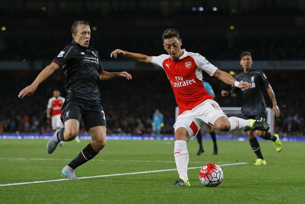 Arsenal's Mesut Ozil, right, challenges for the ball with Liverpool's Lucas Leiva during the English Premier League soccer match between Arsenal and Liverpool at Emirates stadium in London, Monday, Aug. 24, 2015. (AP Photo/Kirsty Wigglesworth)