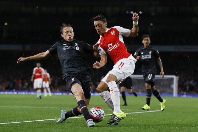 Arsenal's Mesut Ozil, right, challenges for the ball with Liverpool's Lucas Leiva during the English Premier League soccer match between Arsenal and Liverpool at Emirates stadium in London, Monday, Aug. 24, 2015. (AP Photo/Kirsty Wigglesworth)