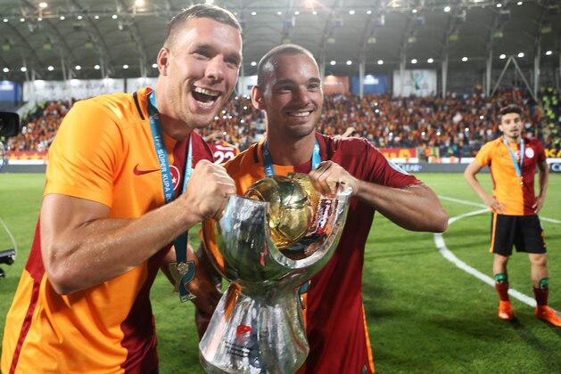 Galatasaray's Polish forward Lukas Podolski (L) and Dutch midfielder Wesley Sneijder celebrate with the trophy after winning the 2015 Turkish Super Cup final match against Bursaspor at Osmanli Stadium on August 08, 2015 in Ankara. Galatasaray defeated Bursaspor 1-0. AFP PHOTO / ADEM ALTAN        (Photo credit should read ADEM ALTAN/AFP/Getty Images)
