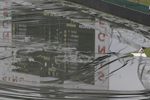 A member of the ground staff walks past the covered ground following a spell of rain during the day one of the third test cricket match between Sri Lanka and India, in Colombo, Sri Lanka, Friday, Aug. 28, 2015. (AP Photo/Eranga Jayawardena)