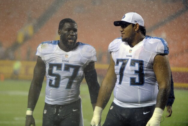 Tennessee Titans linebacker Justin Staples (57) and defensive tackle Toby Johnson (73) walk off the field in the pouring rain as a preseason NFL football game against the Kansas City Chiefs at Arrowhead Stadium in Kansas City, Mo., was suspended Friday, Aug. 28, 2015. (AP Photo/Ed Zurga)