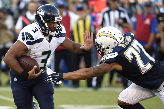 Seattle Seahawks quarterback Russell Wilson, left, runs past San Diego Chargers defensive back Jimmy Wilson during the first half of an NFL preseason football game Saturday, Aug. 29, 2015, in San Diego. (AP Photo/Denis Poroy)