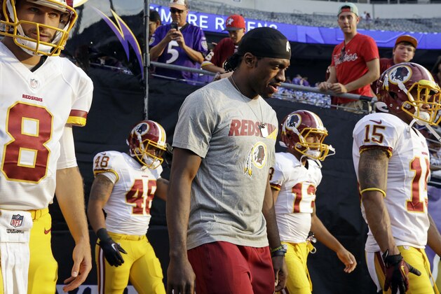 Washington Redskins quarterback Robert Griffin III, center, walks onto the field alongside fellow quarterback Kirk Cousins (8) before a preseason NFL football game against the Baltimore Ravens, Saturday, Aug. 29, 2015, in Baltimore. (AP Photo/Patrick Semansky)