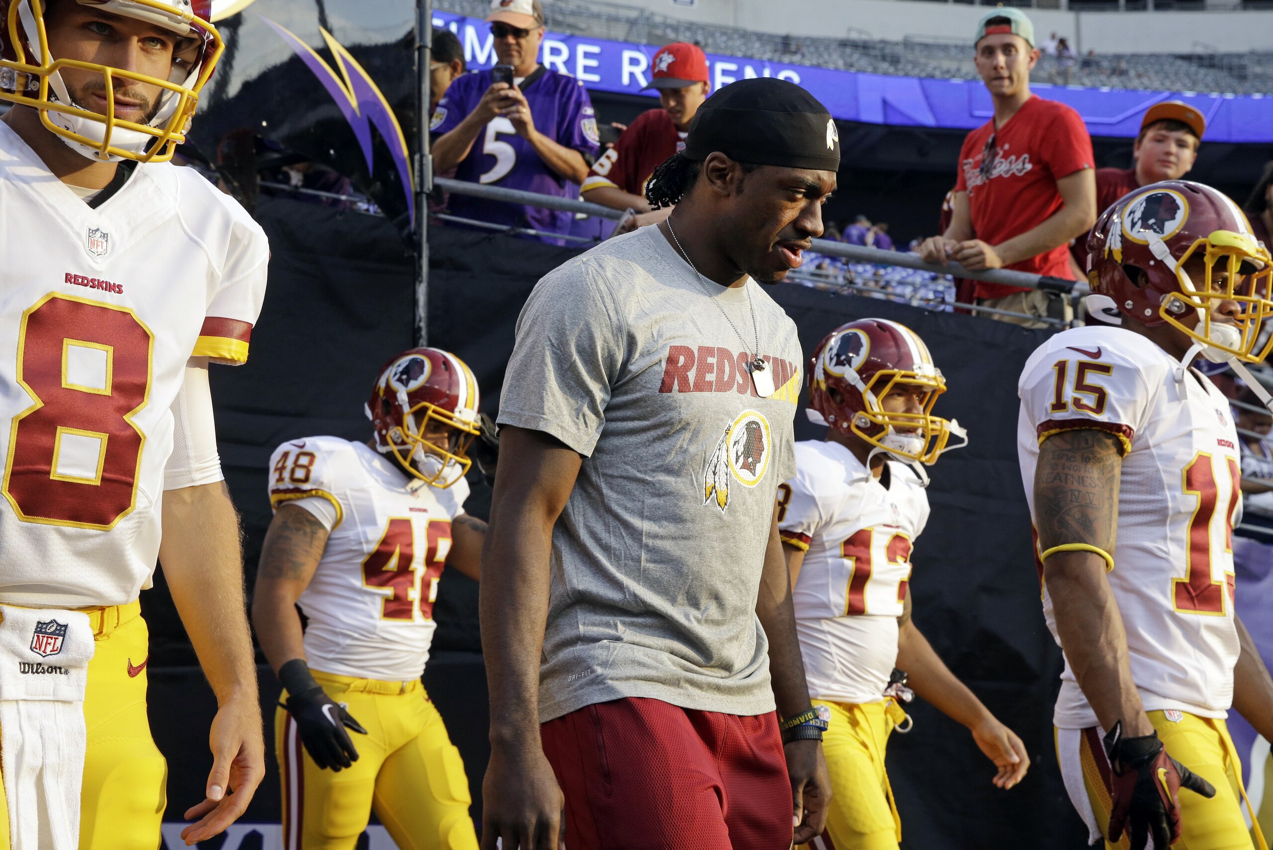 Washington Redskins quarterback Robert Griffin III, center, walks onto the field alongside fellow quarterback Kirk Cousins (8) before a preseason NFL football game against the Baltimore Ravens, Saturday, Aug. 29, 2015, in Baltimore. (AP Photo/Patrick Semansky)