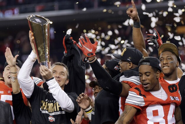 FILE - In this Jan. 12, 2015, file photo, Ohio State coach Urban Meyer holds the trophy and celebrates with his team after the NCAA college football playoff championship game against Oregon in Arlington, Texas. Ohio State is the first unanimous preseason No. 1 in The Associated Press college football poll. The defending national champion Buckeyes received all 61 first-place votes from the media panel in the rankings released Sunday, Aug. 23. (AP Photo/Eric Gay, File)
