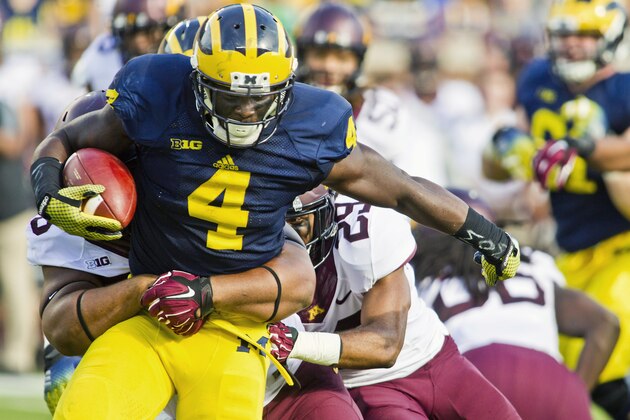 Michigan running back De'Veon Smith (4) tries to break away from Minnesota tackles in the second quarter of an NCAA college football game in Ann Arbor, Mich., Saturday, Sept. 27, 2014. (AP Photo/Tony Ding)