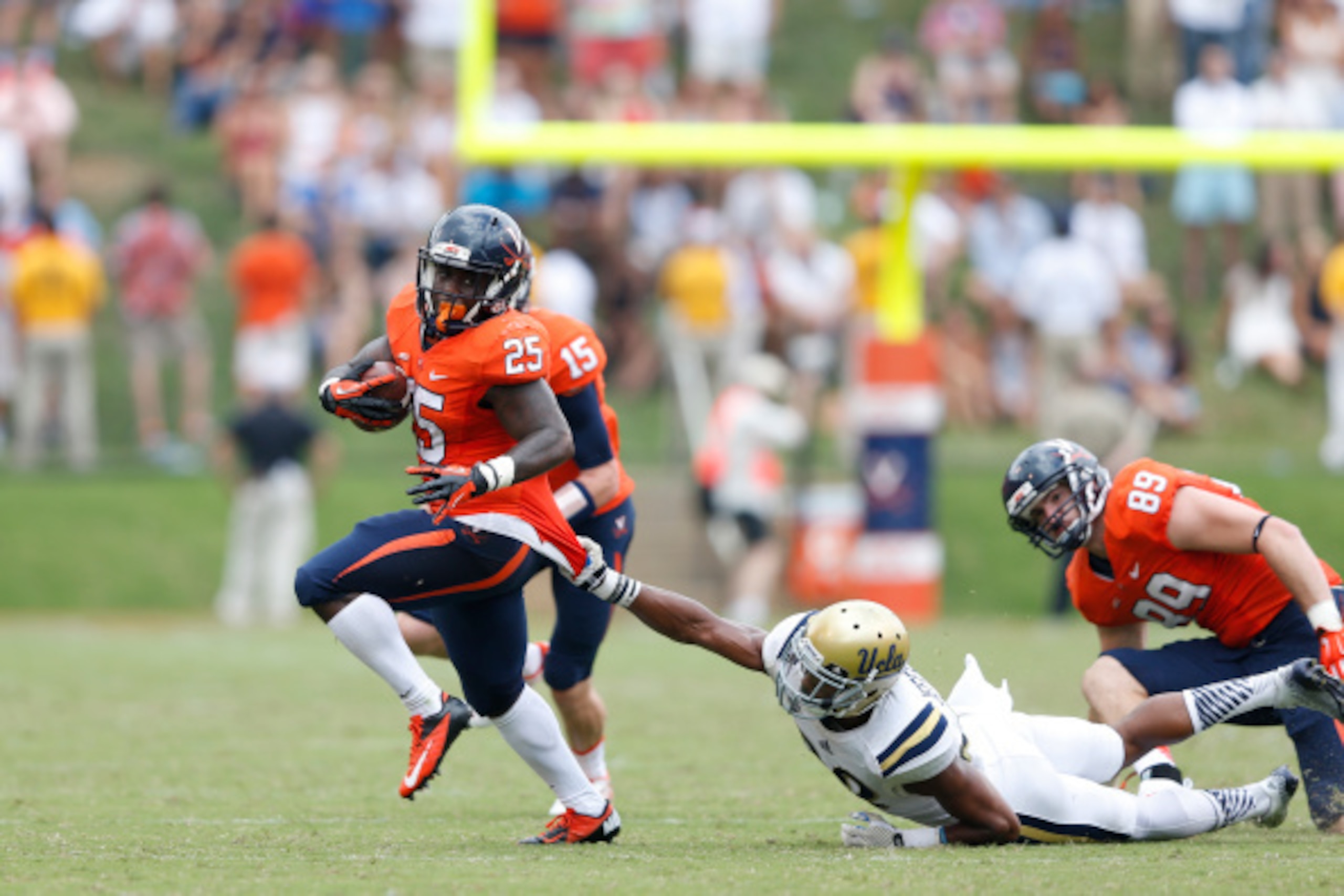 CHARLOTTESVILLE, VA - AUGUST 30: Kevin Parks #25 of the Virginia Cavaliers breaks out of a tackle against Anthony Jefferson #23 of the UCLA Bruins during the game at Scott Stadium on August 30, 2014 in Charlottesville, Virginia. UCLA defeated Virginia 28-20. (Photo by Joe Robbins/Getty Images)