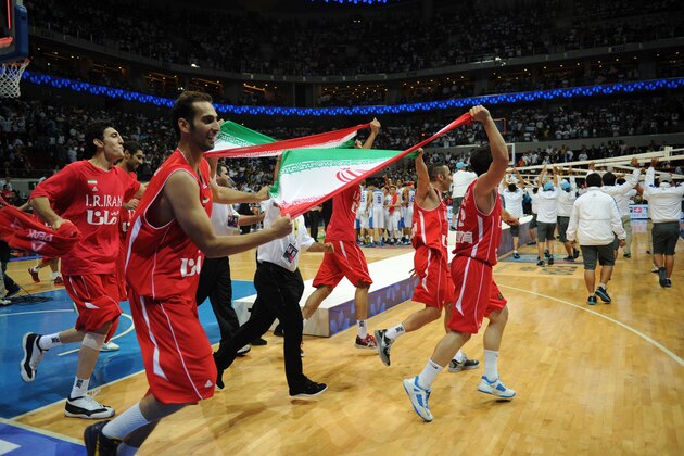 Iranian players and officials carry their national flag and run around the court after defeating the Philippines in the men's Asia championship basketball final game in Manila on August 11, 2013. Iran routed the Philippines 85-71 to bag gold at the 27th FIBA Asian men's basketball championship on August 11.   AFP PHOTO/TED ALJIBE        (Photo credit should read TED ALJIBE/AFP/Getty Images)