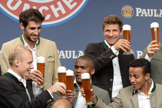 (L-R) Bayern Munich's midfielder Sebastian Rode, Bayern Munich's Spanish midfielder Javi Martinez, Bayern Munich's Brazilian midfielder Douglas Costa, Bayern Munich's striker Thomas Mueller, Bayern Munich's Spanish midfielder Thiago Alcantara, Bayern Munich's Polish striker Robert Lewandowski and Bayern Munich's Spanish midfielder Xabi Alonso salute with beer during a group photo of the German first division Bundesliga football club FC Bayern Munich at the set of a beer advertising photo shoot  in Munich, southern Germany, on August 25, 2015. AFP PHOTO / CHRISTOF STACHE        (Photo credit should read CHRISTOF STACHE/AFP/Getty Images)