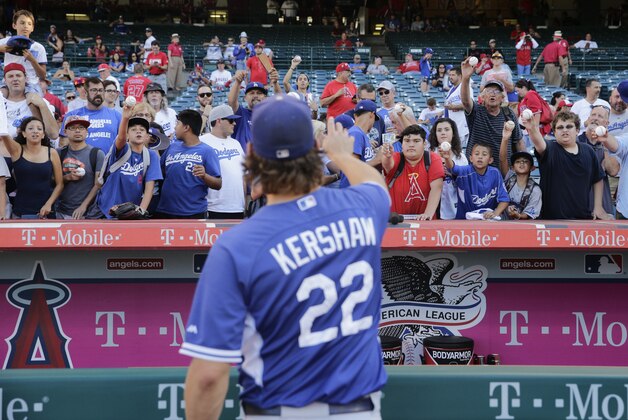 Los Angeles Dodgers starting pitcher Clayton Kershaw tosses the ball back to his fans before a baseball game with the Los Angeles Angels, Monday, Sept. 7, 2015, in Anaheim, Calif. (AP Photo/Jae C. Hong)