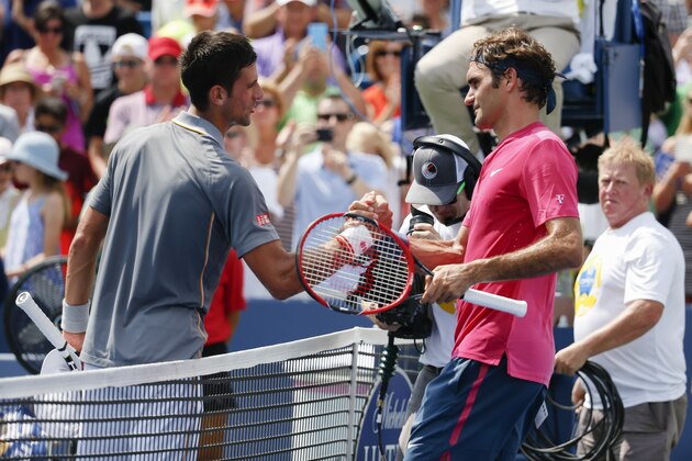 Roger Federer, right, of Switzerland, clasps hands with Novak Djokovic, of Serbia, after the men's final at the Western & Southern Open tennis tournament, Sunday, Aug. 23, 2015, in Mason, Ohio. Federer defeated Djokovic 7-6 (1), 6-3. (AP Photo/John Minchillo)