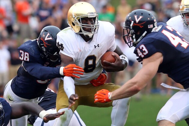 Notre Dame quarterback Malik Zaire (8) is tackled by Virginia safety Kelvin Rainey (38) and Trent Corney (43) during an NCAA college football game Saturday, Sept. 12, 2015, in Charlottesville, Va. Zaire was injured and eventually driven off the field. Notre Dame defeated Virginia 34-27. (AP Photo/Andrew Shurtleff)