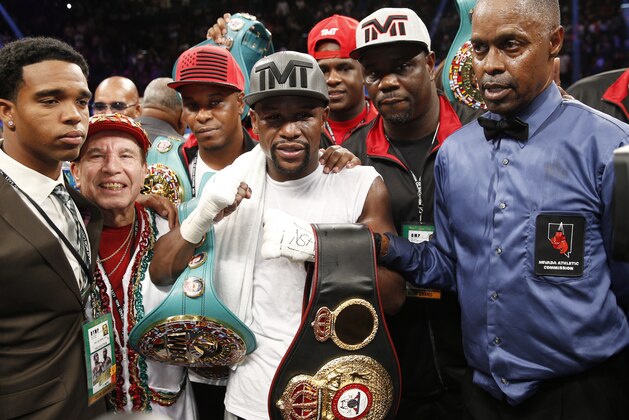 Floyd Mayweather Jr., center, stands with referee Kenny Bayless, right, after defeating Andre Berto during their welterweight title boxing bout Saturday, Sept. 12, 2015, in Las Vegas. (AP Photo/Steve Marcus)