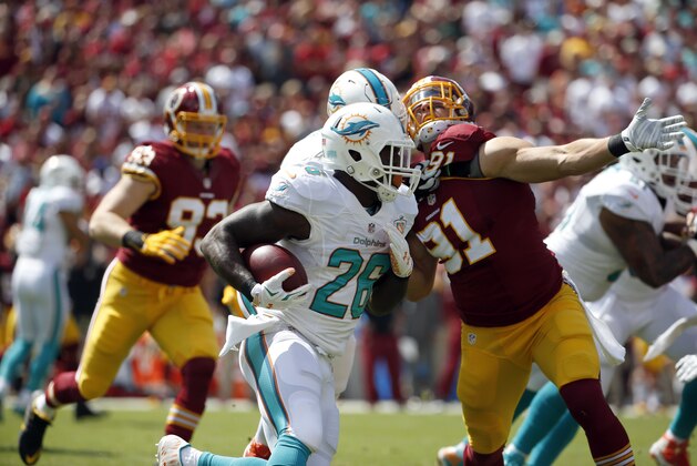 Miami Dolphins running back Lamar Miller (26) runs past Washington Redskins outside linebacker Ryan Kerrigan (91) during the first half of an NFL football game Sunday, Sept. 13, 2015, in Landover, Md. (AP Photo/Evan Vucci)