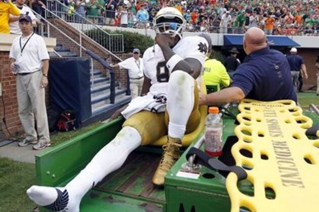Notre Dame quarterback Malik Zaire (8) is driven off the field after injuring his right ankle during an NCAA college football game against Virginia, Saturday, Sept. 12, 2015, in Charlottesville, Va.  Notre Dame defeated Virginia 34-27. (AP Photo/Andrew Shurtleff)