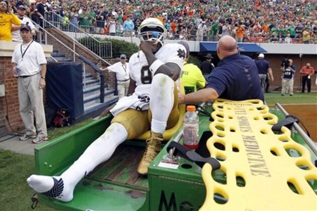 Notre Dame quarterback Malik Zaire (8) is driven off the field after injuring his right ankle during an NCAA college football game against Virginia, Saturday, Sept. 12, 2015, in Charlottesville, Va.  Notre Dame defeated Virginia 34-27. (AP Photo/Andrew Shurtleff)