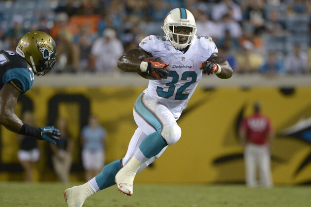Miami Dolphins running back Jonas Gray (32) rushes past Jacksonville Jaguars free safety Josh Evans, left, during the second half of an NFL preseason football game in Jacksonville, Fla., Friday, Aug. 9, 2013. (AP Photo/Phelan M. Ebenhack)
