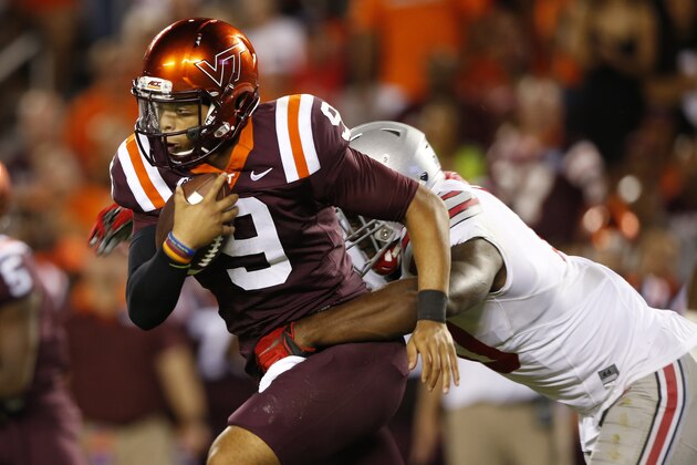 Virginia Tech quarterback Brenden Motley (9) gains yardage as Ohio State defensive lineman Jalyn Holmes makes the stop during the second half of an NCAA college football game in Blacksburg, Va., Monday, Sept. 7, 2015. (AP Photo/Steve Helber)
